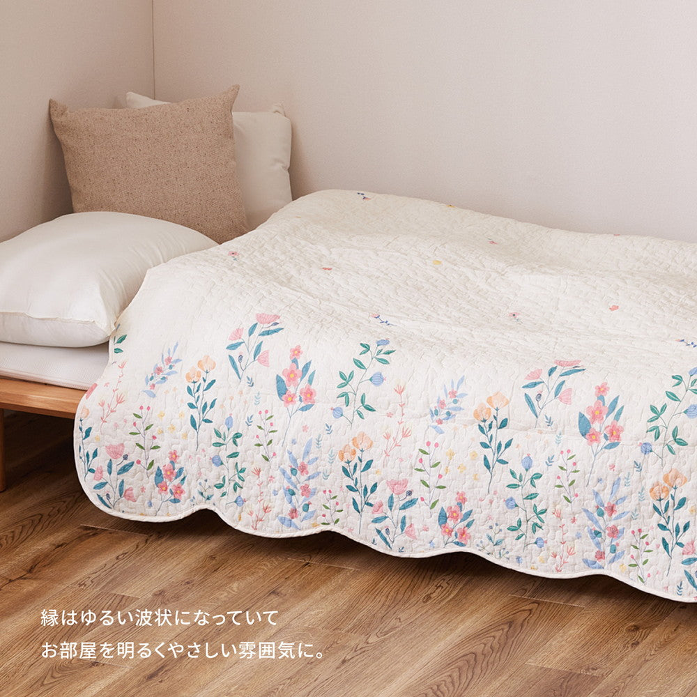 アイボリーの優しい色合いにカラフルな花柄がプリントされたキルトのマルチカバー